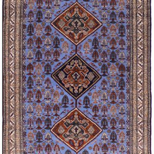 An antique rug with a periwinkle blue background, gold/brown border, and intricate design
